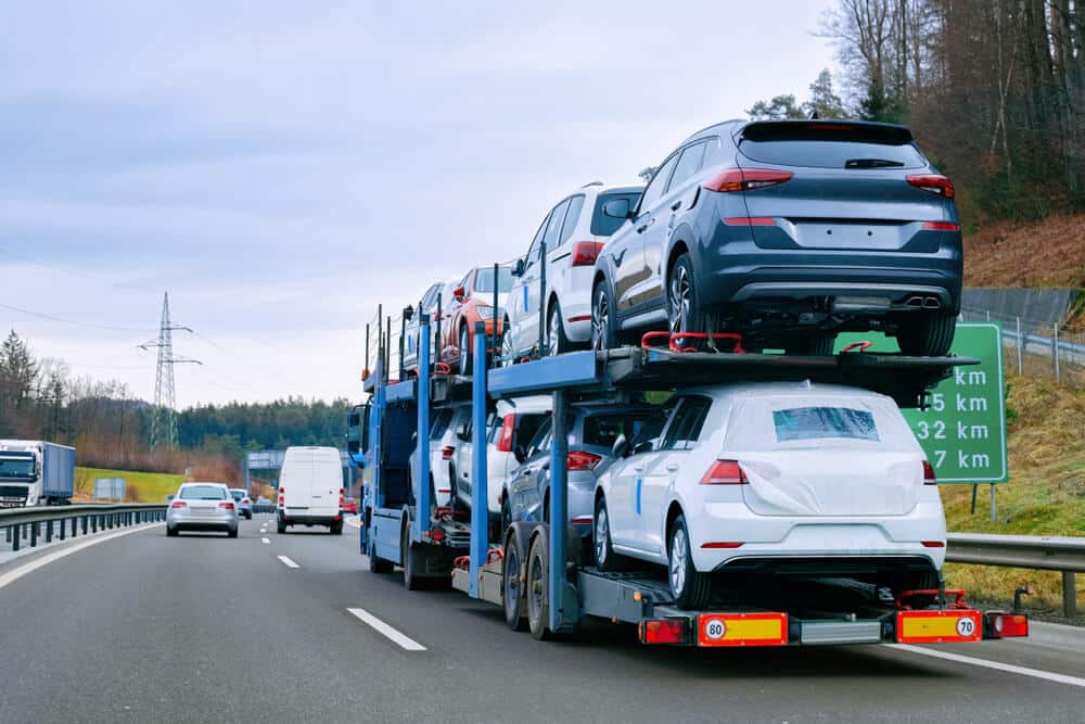 Open Auto Transport Service - First Line Transport INC Open auto transport truck carrying multiple vehicles on highway - professional car shipping service